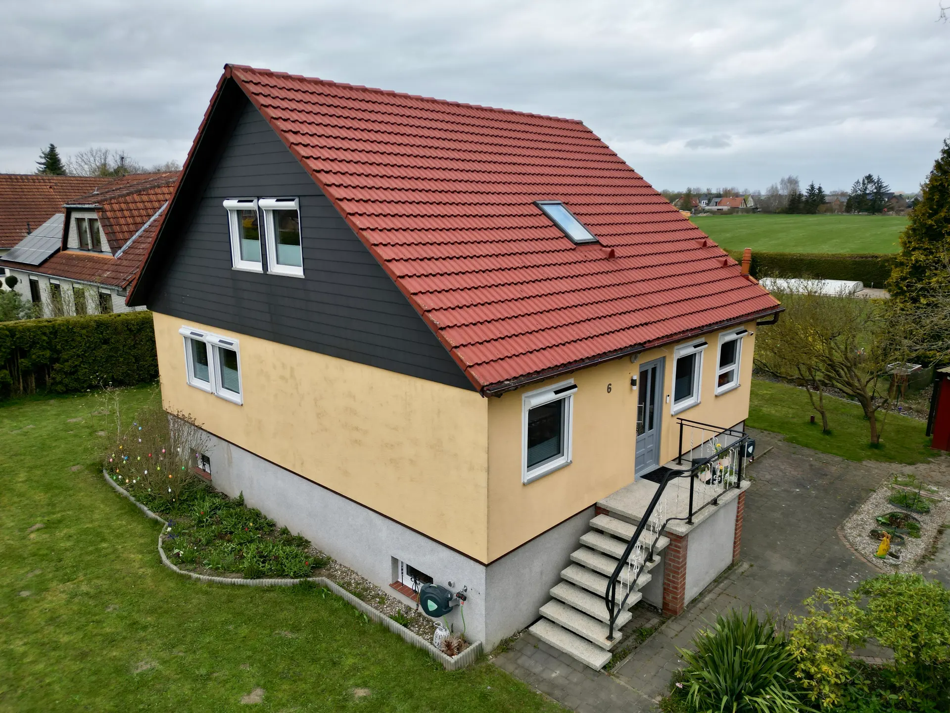 Haus vor der Renovierung - verblasstes Gelb und rotes Dach